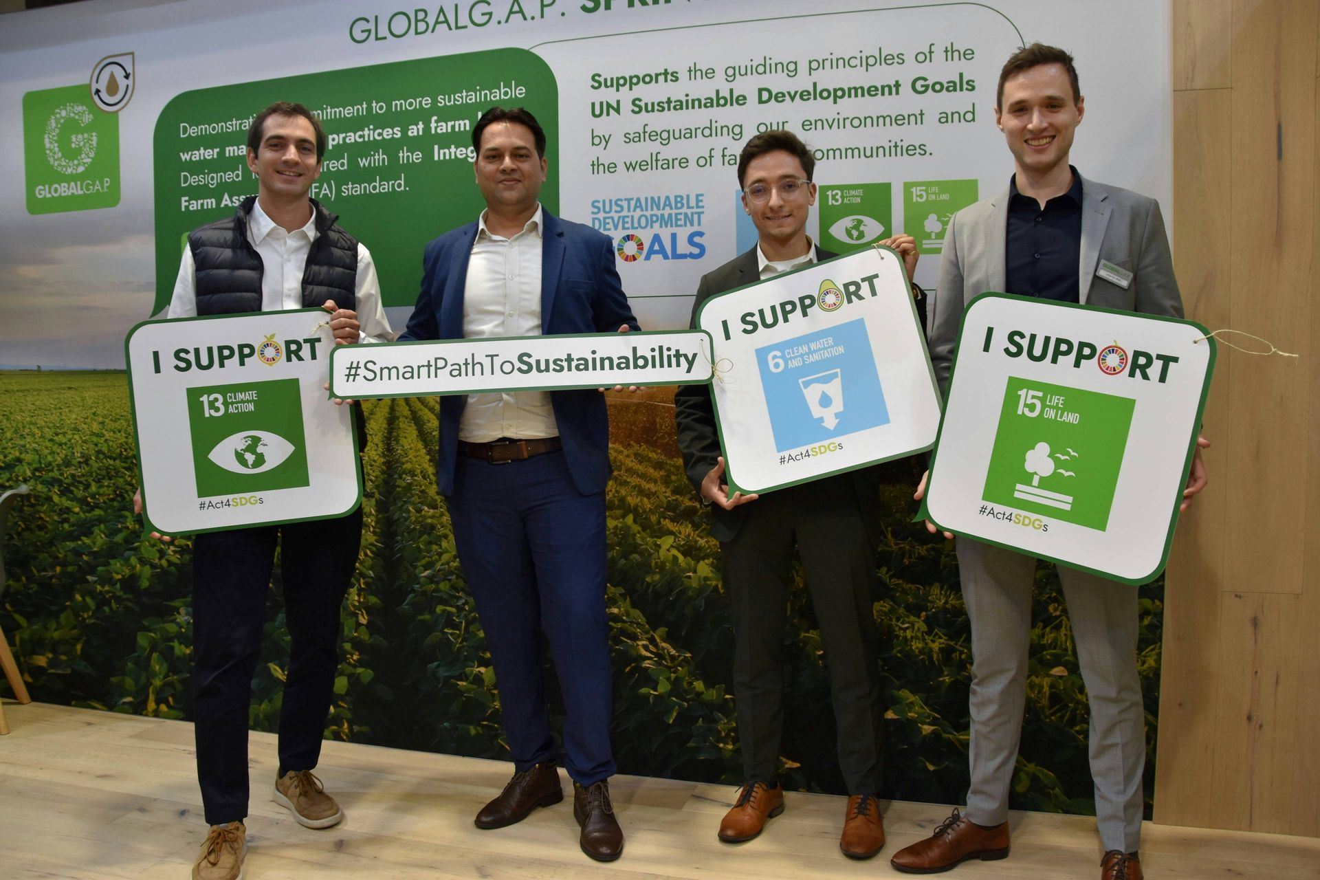 UPL Ltd member representative and GLOBALG.A.P. representatives holding SDG-related signs at Fruit Logistica 2024 in Berlin, Germany.