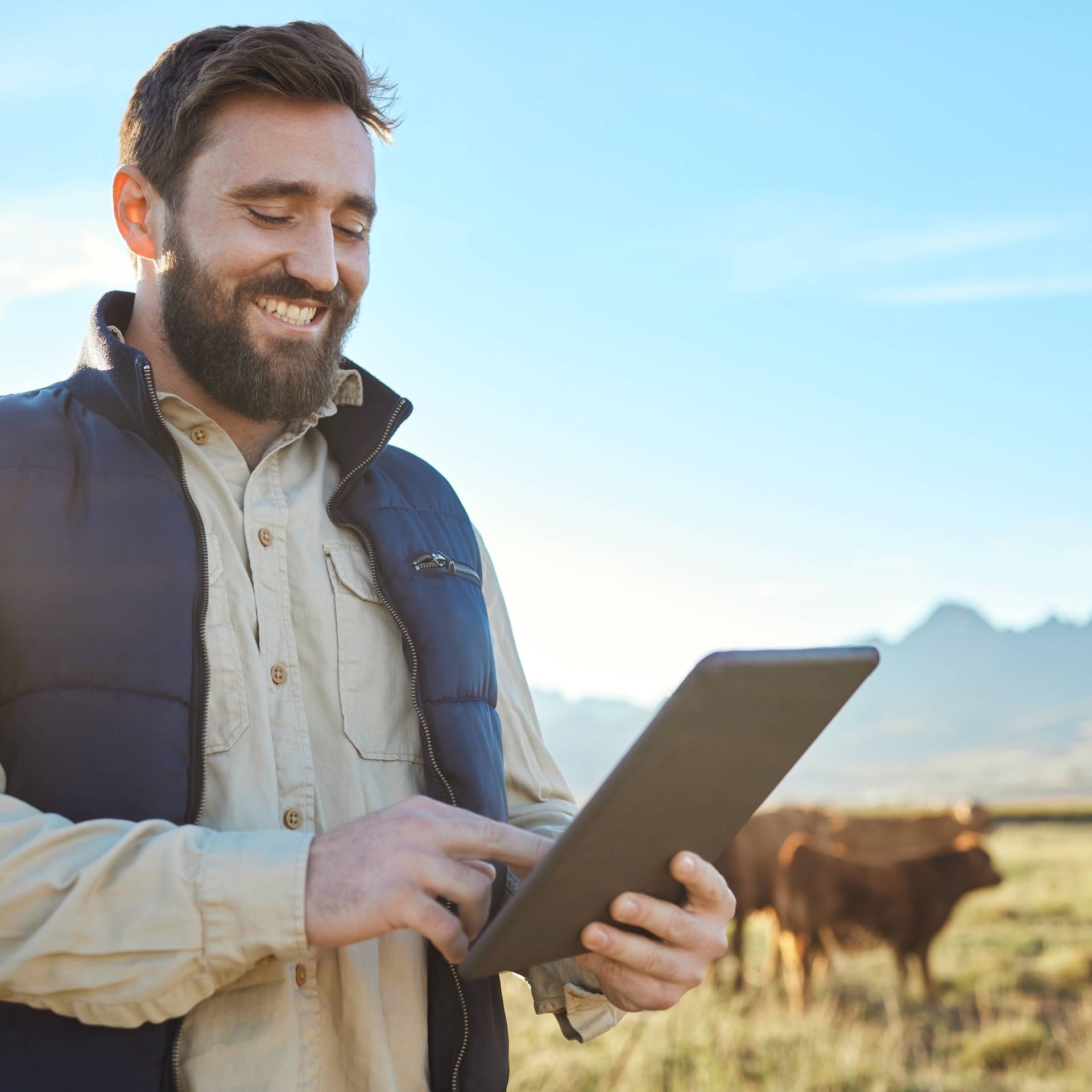 Image of a livestock farmer using a tablet in a field