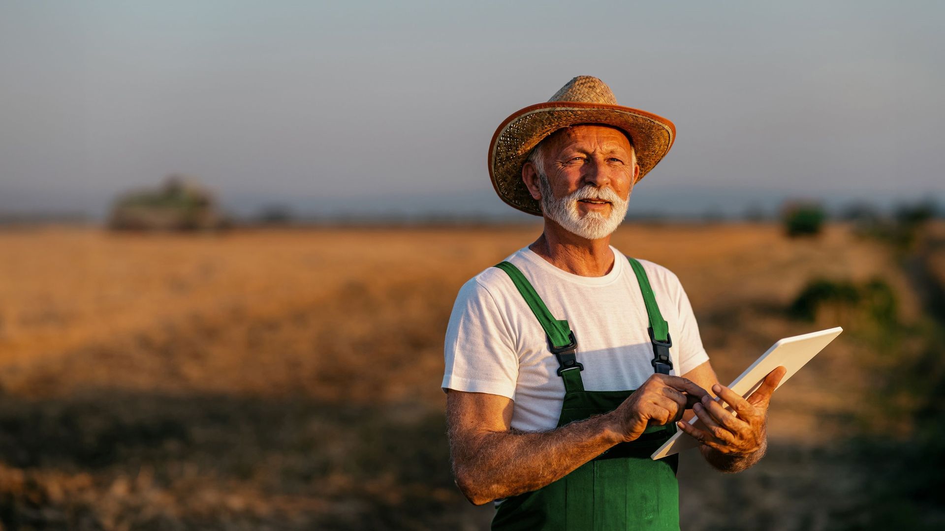 Image of a farmer with a tablet standing in a field