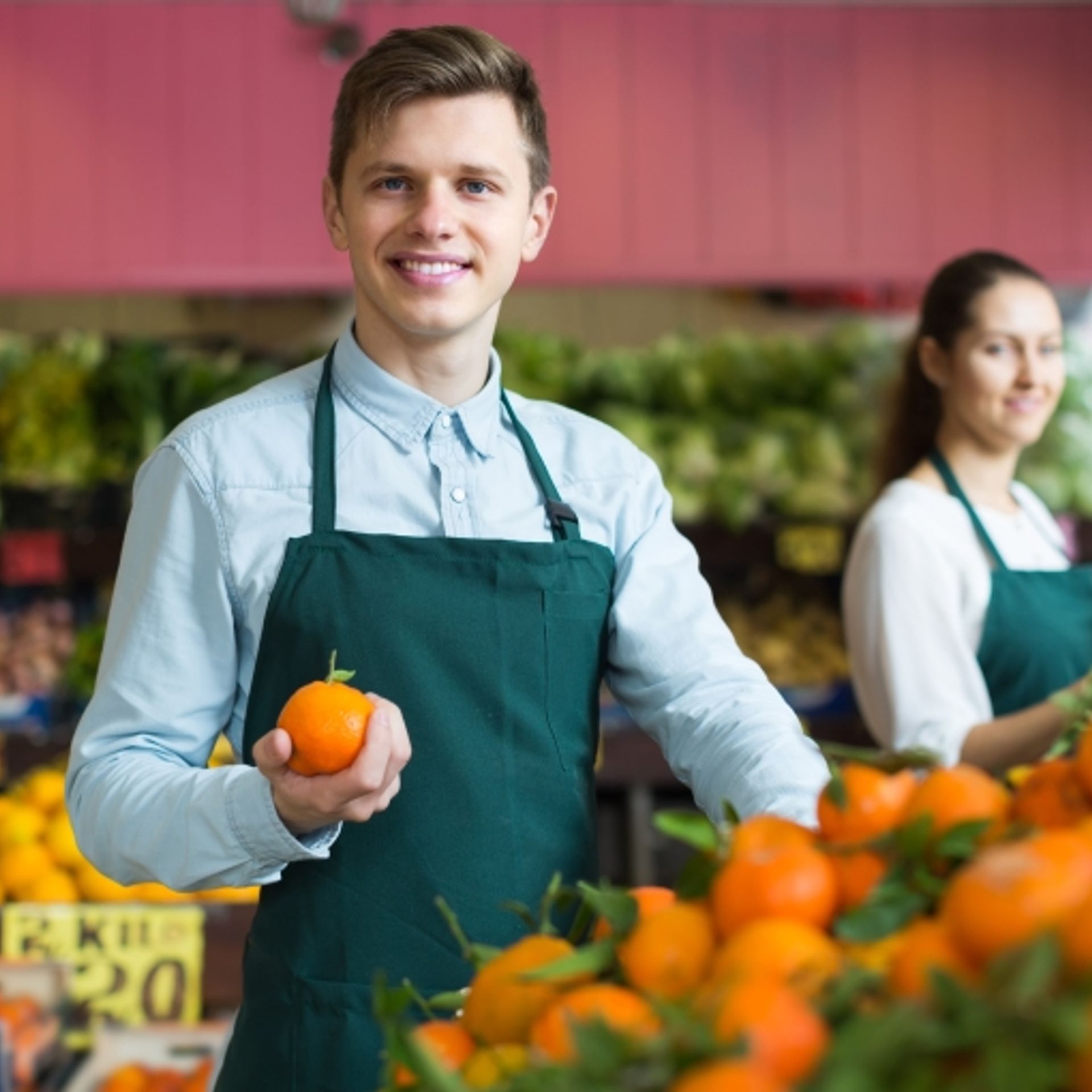 Image of a retail worker displaying fresh fruit products in store
