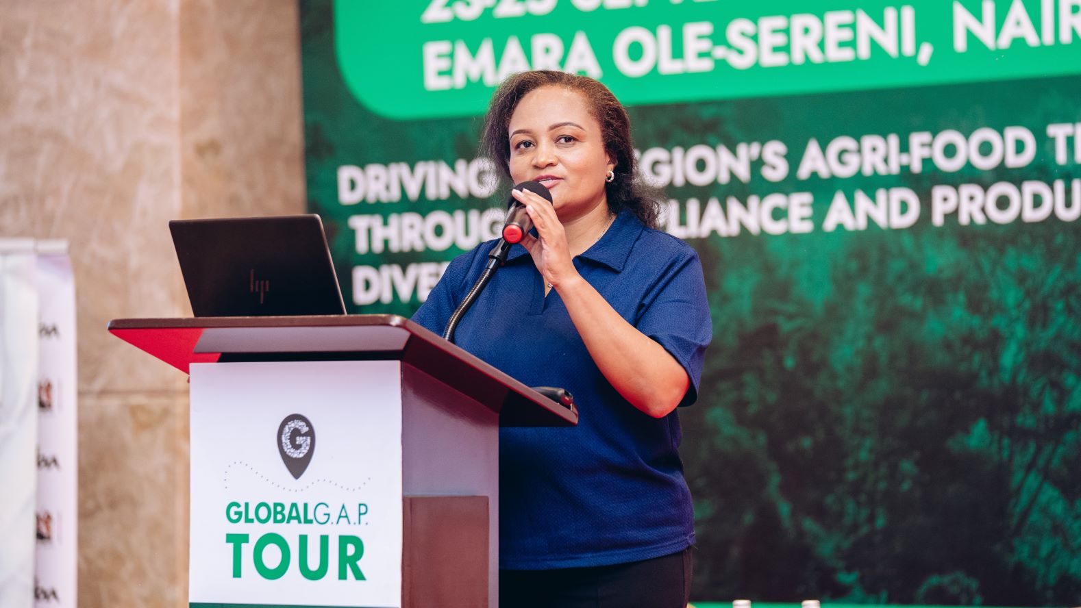 The organizer, Dr. Charity Mutegi, on stage at the 2025 GLOBALG.A.P. TOUR stop in Nairobi, Kenya.